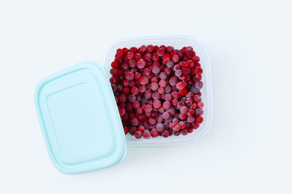 Plastikdose mit eingefrorenen Cranberrys.