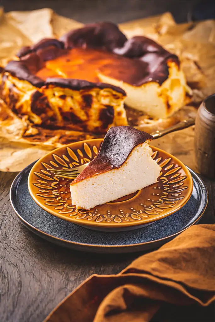 Ein aufgeschnittenes Stück Käsekuchen liegt auf Omas Teller mit einer Kuchengabel.