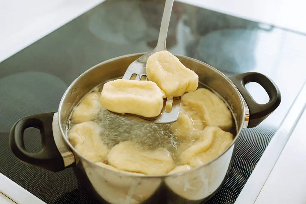 Omas Kartoffelknödel kochen in einem Topf mit Wasser.